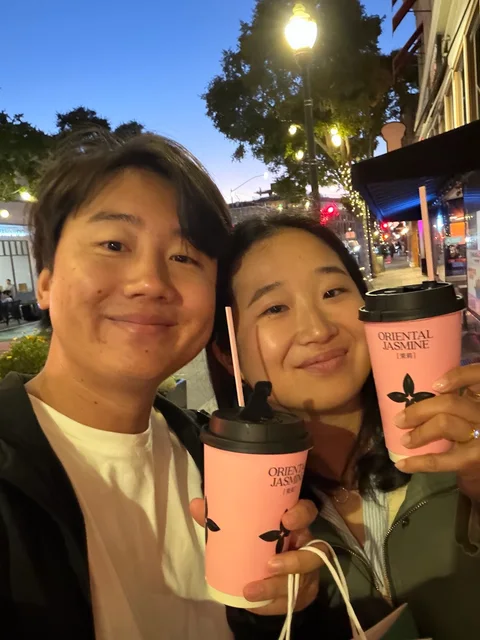 Nam-Hee and Hiroo holding takeaway cups on a city street at night.