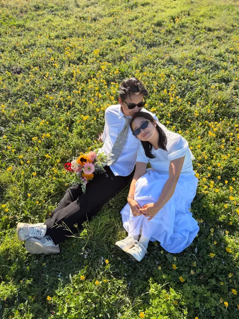 Nam-Hee and Hiroo sitting close together in a grassy field.