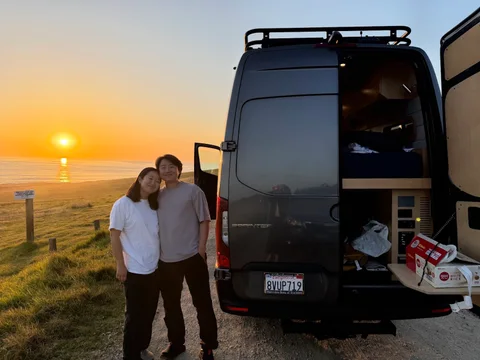 Nam-Hee and Hiroo beside a camper van at sunset.