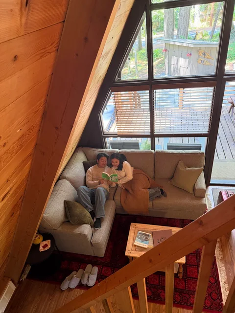 Nam-Hee and Hiroo sitting together on a sofa in a wooden cabin.