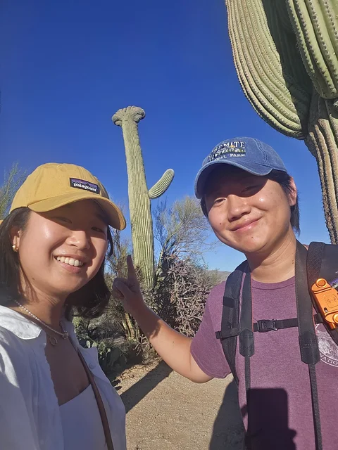 Nam-Hee and Hiroo smiling beside a tall cactus.
